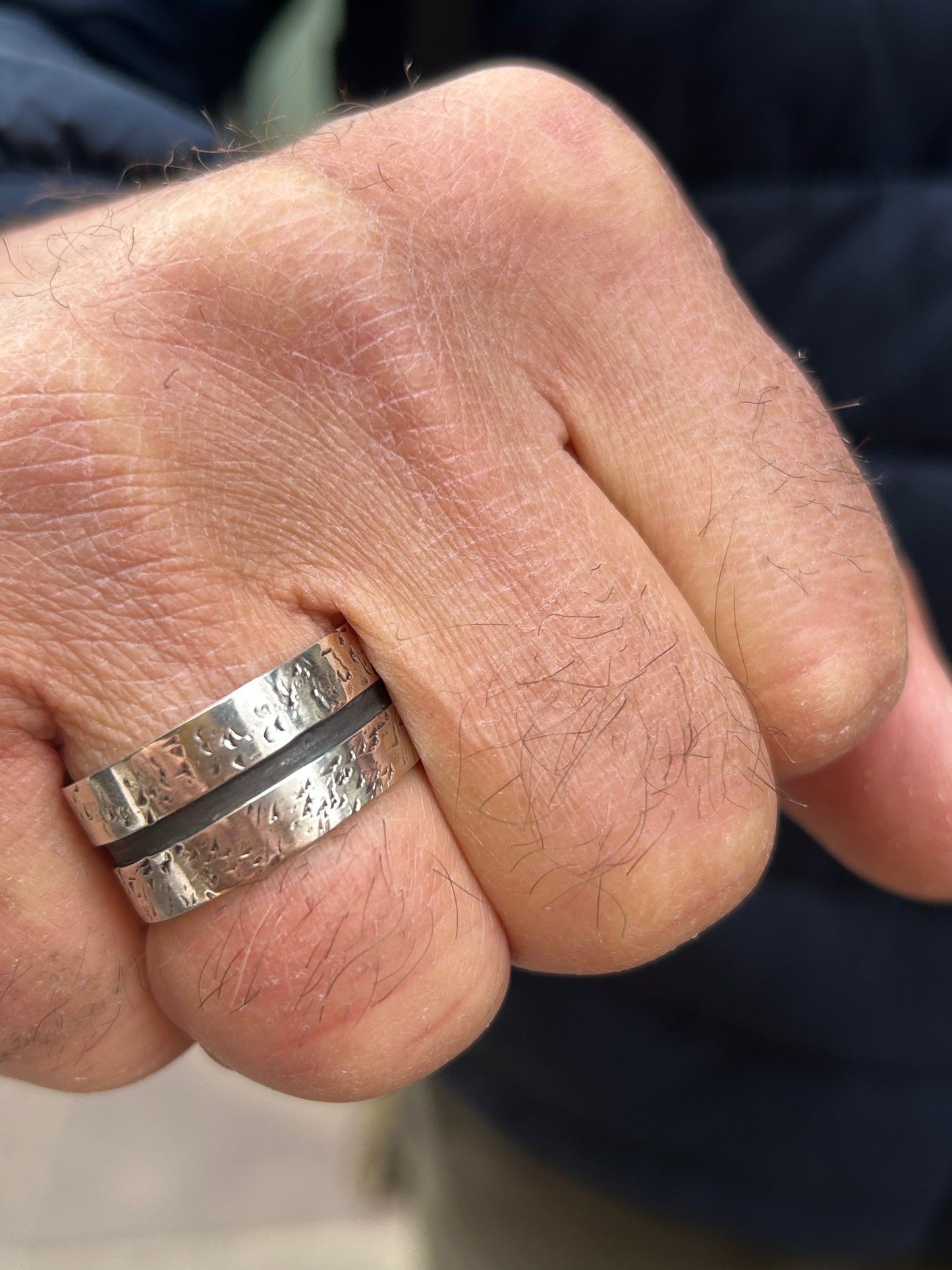 Anello uomo in argento 925 con texture martellata e fascia centrale brunita indossato su mano