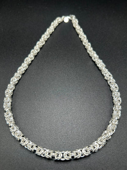 Argento che sembra intrecciato come un tessuto. Questa collana nasce dalla lavorazione della maglia bizantina, una successione articolata di anelli che crea una struttura compatta, morbida e tridimensionale.

Il risultato è un gioiello importante ma estremamente portabile, nel quale la ricchezza della trama diventa protagonista senza bisogno di pietre o altri elementi decorativi.