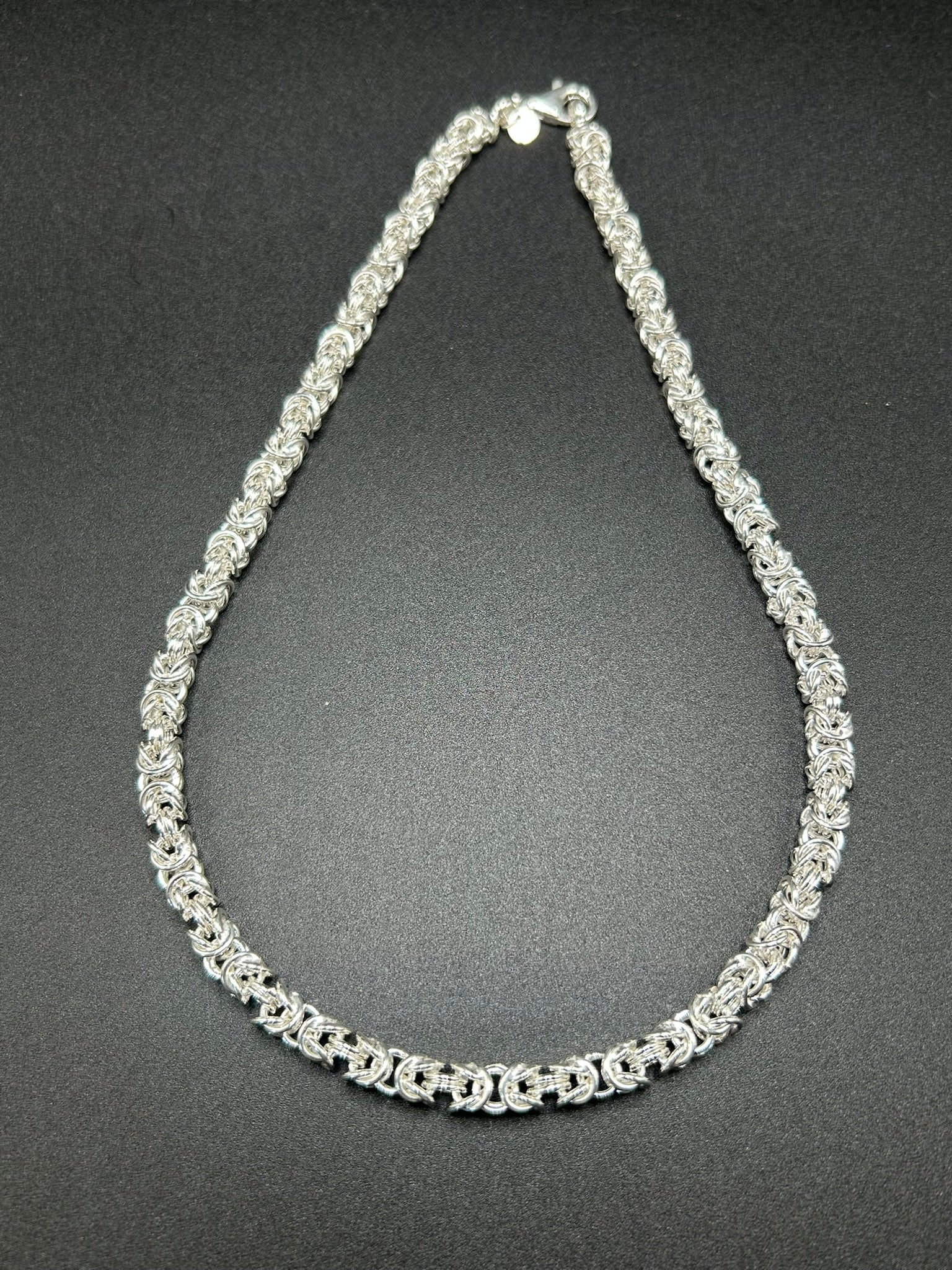 Una collana importante, costruita interamente attraverso l’intreccio della tradizionale maglia bizantina. I singoli elementi in argento sterling 925 si susseguono creando una trama ricca e tridimensionale, capace di catturare la luce e dare carattere al gioiello.

E' una collana dal design deciso ma senza tempo, pensata per essere indossata da sola come protagonista.