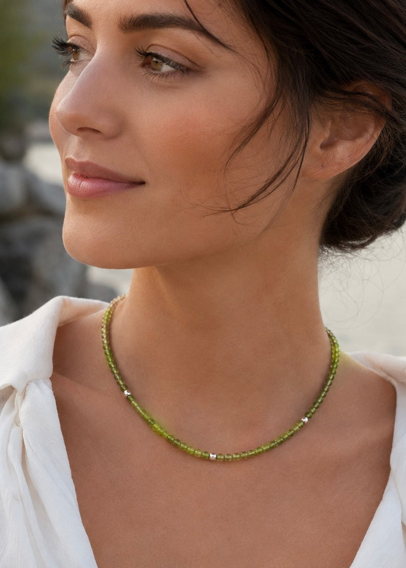 Woman wearing a handmade natural peridot necklace with graduated faceted rondelle beads and three sterling silver 925 spacers by De Giorgi Gioielli.